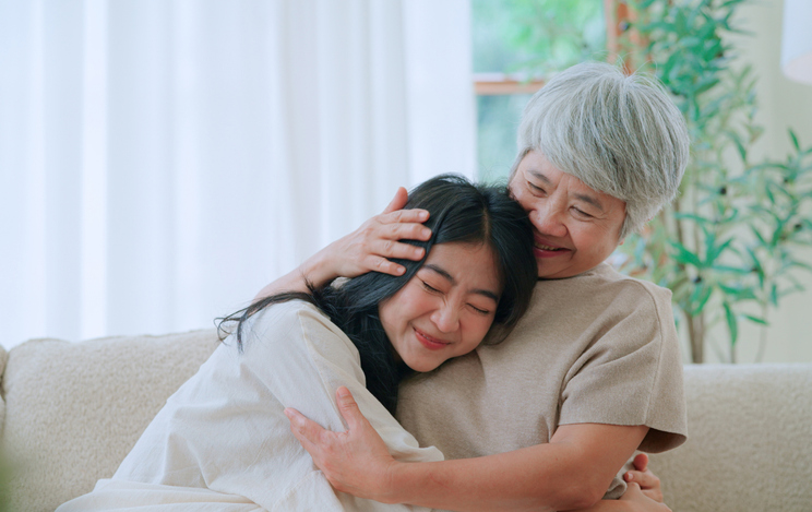 Mother and daughter hugging together in living room